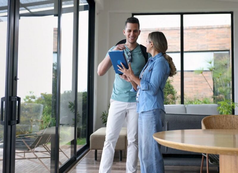 momak i devojka stoje na sred kuće i gledaju nešto na tabletu