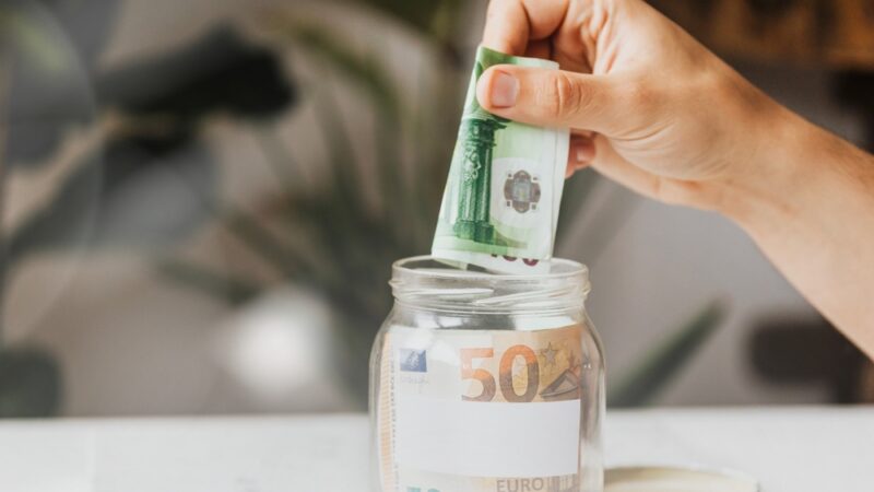 Osoba ubacuje novac u teglu kao simbol štednje i smanjenja troškova kredita
